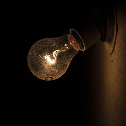 Eine Glühbirne versucht gegen das Dunkel anzuleuchten